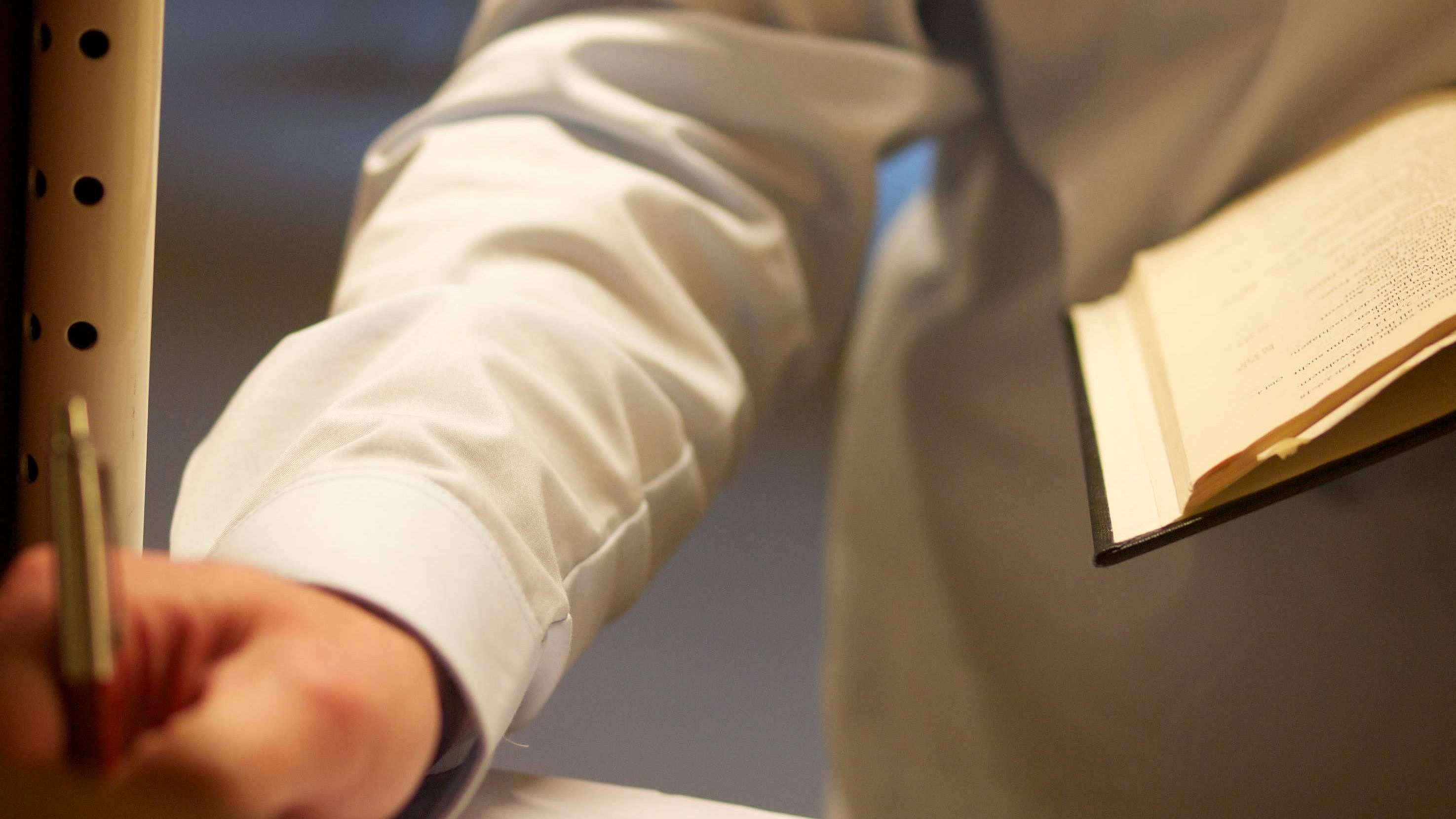 Symbolbild: Eine Person hält in der linken Hand ein Buch und notiert mit rechts etwas
